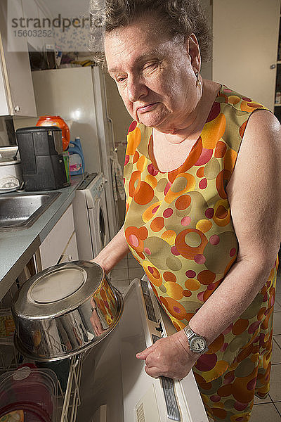 Blinde Seniorin benutzt ihre Spülmaschine in der Küche