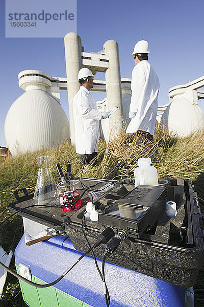 Wasserprobe und PH-Meter mit zwei Wissenschaftlern im Hintergrund