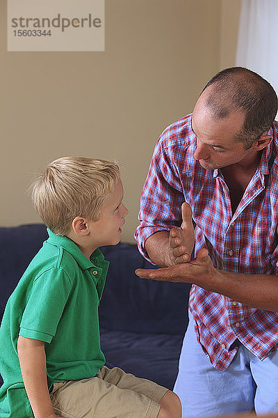 Vater und Sohn mit Hörbehinderung gebärden Stopp in amerikanischer Zeichensprache