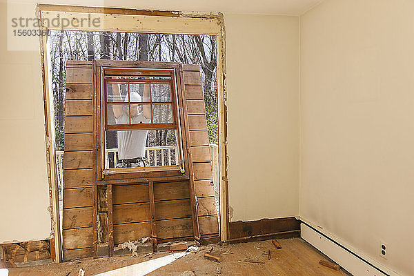Hispanischer Schreiner beim Entfernen der neu geschnittenen Tür zum Deck eines Hauses
