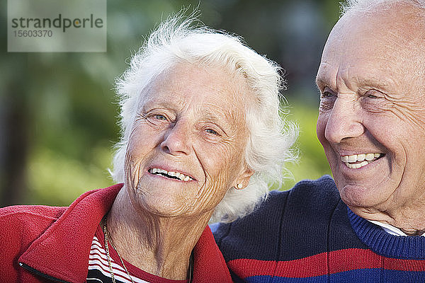 Porträt eines lächelnden älteren Paares in einem Park.
