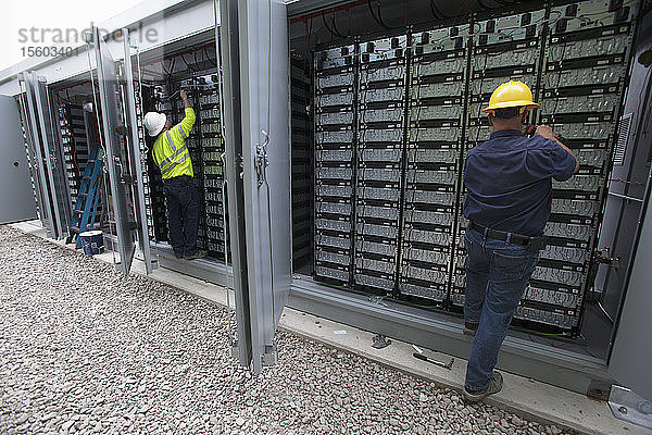 Ingenieure  die Energiespeicherbatterien zur Notstromversorgung eines Kraftwerks anschließen