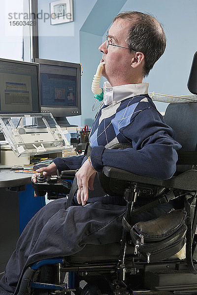 Geschäftsmann mit Duchenne-Muskeldystrophie in einem motorisierten Rollstuhl  der ein Beatmungsgerät benutzt