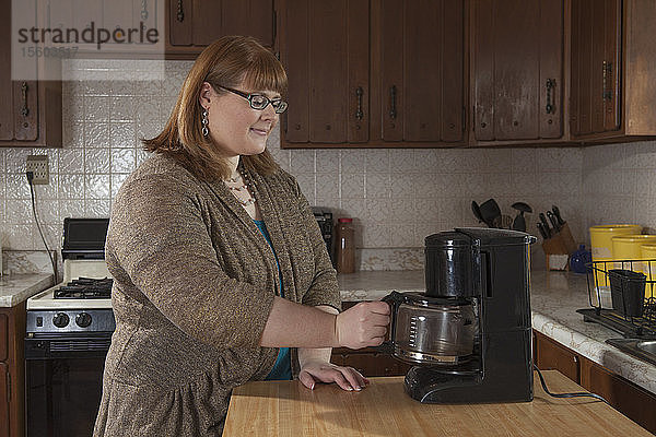 Eine blinde Frau kocht Kaffee in ihrer Küche