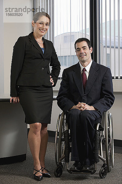 Porträt einer Geschäftsfrau  die neben einem Geschäftsmann mit Rückenmarksverletzung steht