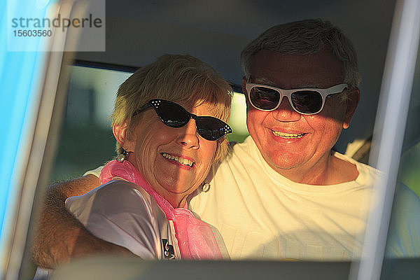 Porträt eines glücklichen älteren Paares  das in einem Auto sitzt