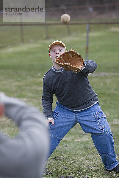 Behinderter Mann spielt Baseball mit seinem Sohn Behinderter Mann lächelt mit seinem Sohn mit Down-Syndrom