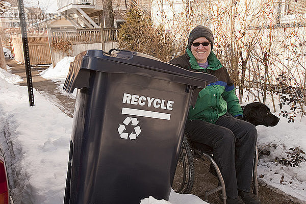 Frau mit Multipler Sklerose macht Recycling mit einem Diensthund im Winter