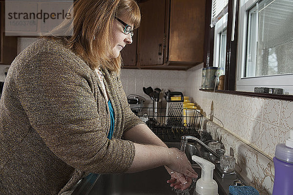 Eine blinde Frau  die in ihrer Küche Geschirr spült