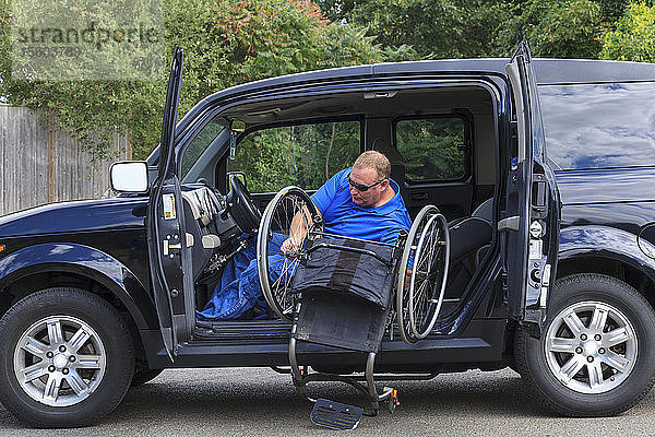 Ein Mann mit einer Rückenmarksverletzung setzt seinen Rollstuhl zusammen  um sein Auto zu verlassen