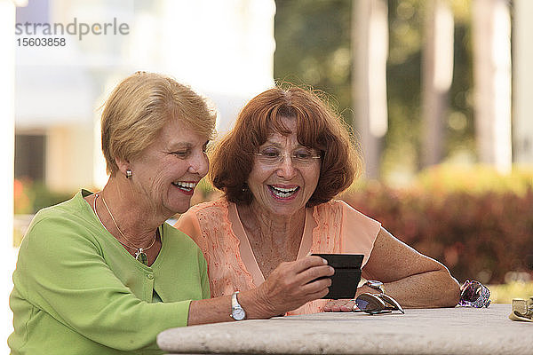 Ältere Freunde schauen auf ein Smartphone und lächeln