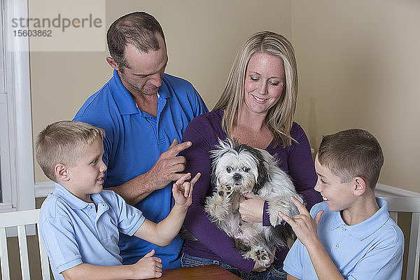 Um einen Tisch sitzende Familie mit Hörbehinderung  die Love and New Puppy in amerikanischer Zeichensprache beschreibt