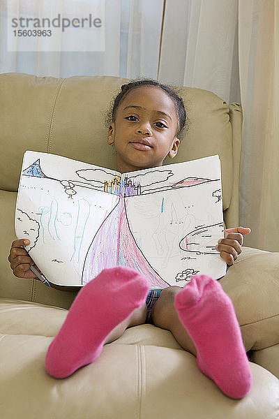 Hispanisches Mädchen sitzt und zeigt eine Zeichnung