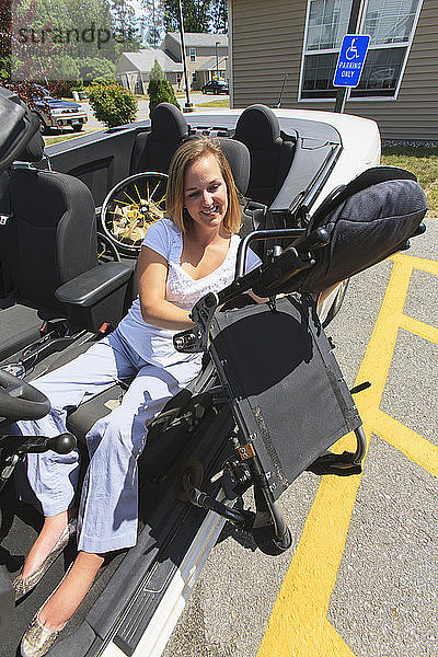 Frau mit Querschnittslähmung zieht den Stuhl aus dem Rollstuhl in ihr adaptives Fahrzeug