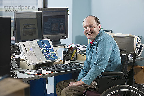 Geschäftsmann mit Friedreich-Ataxie im Rollstuhl in einem Büro