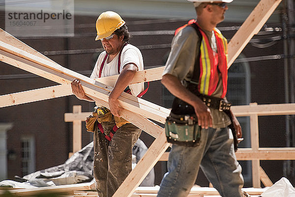 Zimmerleute tragen Holzbretter auf einer Baustelle