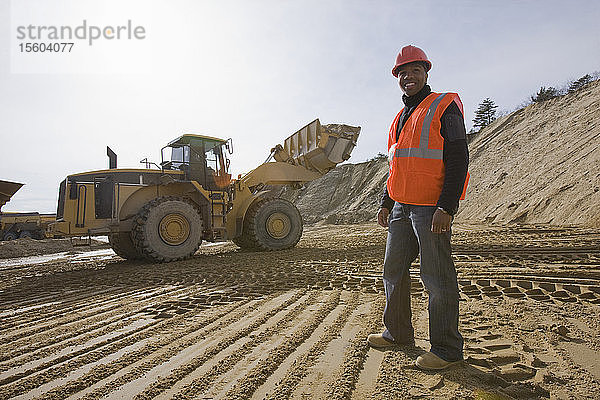 Ingenieur auf einer Baustelle mit einem Frontlader im Hintergrund