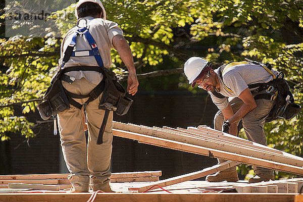 Zimmerleute beim Aufnehmen eines Dachgiebels auf einer Baustelle