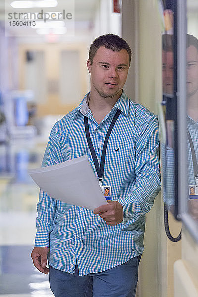 Junger Mann mit Down-Syndrom erledigt Papierkram in einem Krankenhaus