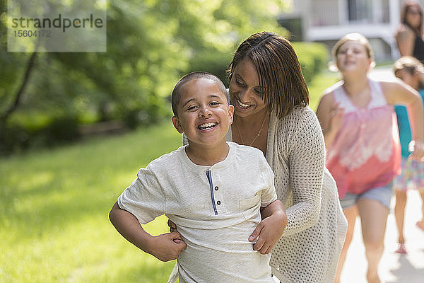 Hispanischer Junge mit Autismus spielt draußen mit seiner Familie