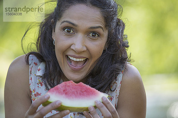 Porträt einer glücklichen hispanischen Frau  die eine Wassermelone isst