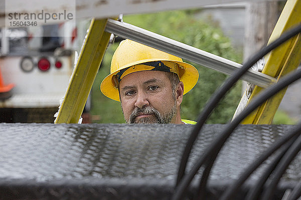 Arbeiter eines Versorgungsunternehmens bereitet sich auf den Einsatz einer Leiter auf der Baustelle vor