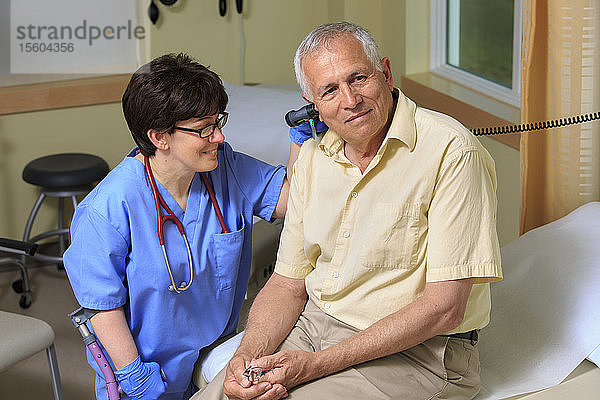 Krankenschwester mit Zerebralparese prüft die Ohren eines Patienten in einer Klinik