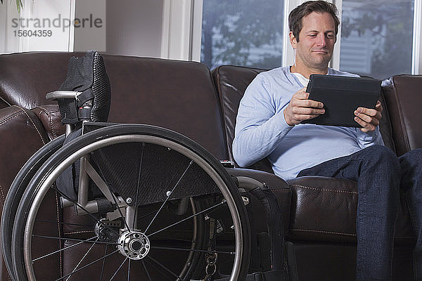 Mann mit Rückenmarksverletzung liest ein Tablet