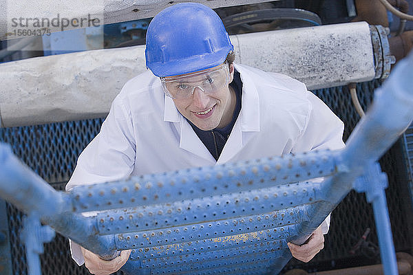 Laborarbeiter klettert in einem Asphaltwerk auf eine Leiter