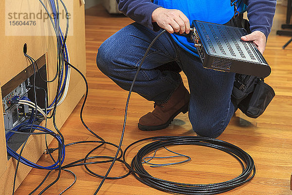 Servicemitarbeiter  der das Kabel an die Modembox für das Heimfernsehen anschließt