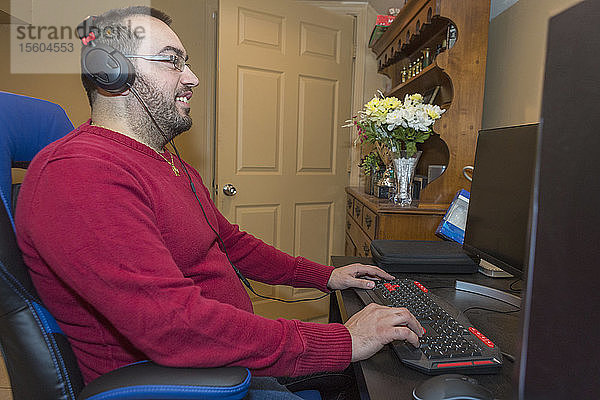 Mann mit Sehbehinderung an seiner Tastatur mit einem Bildschirmlesegerät