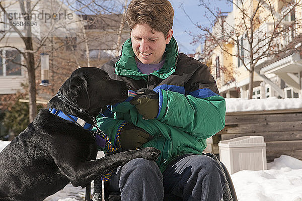 Frau mit Multipler Sklerose übergibt Schlüssel an einen Diensthund im Schnee