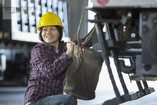 Weiblicher Energietechniker beim Anbringen einer Schaufel auf einem Gerätewagen