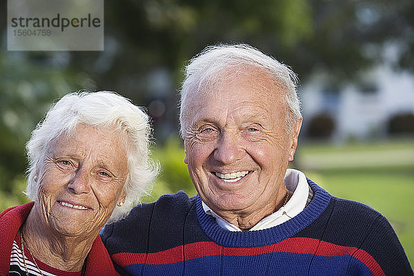 Porträt eines lächelnden älteren Paares in einem Park.