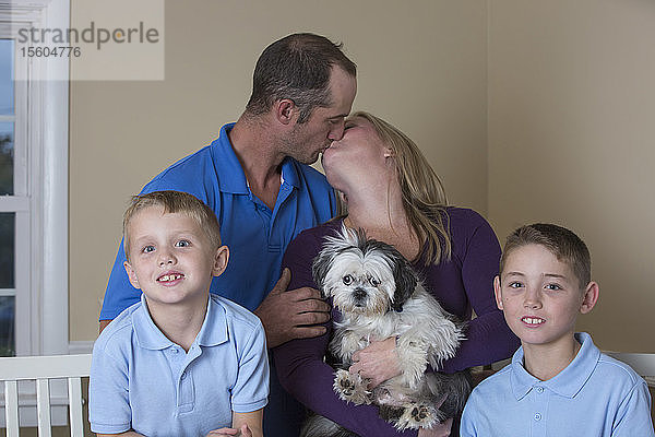 Porträt einer glücklichen Familie mit Hörbehinderung und küssenden Eltern