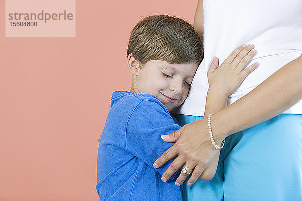 Seitenansicht eines Jungen  der seine Mutter umarmt.
