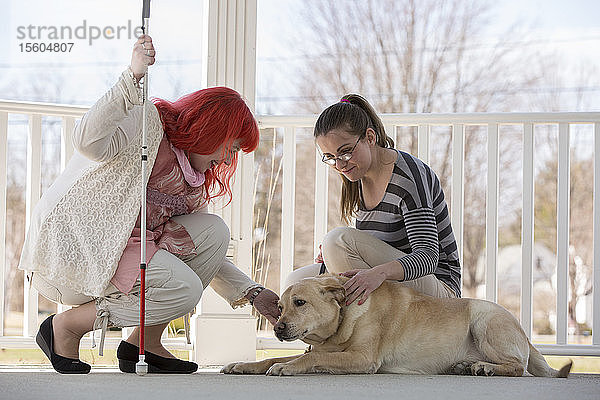 Zwei Frauen mit Sehbehinderungen  eine mit einem Diensthund und eine mit einem Blindenstock