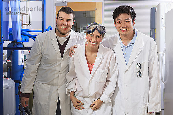 Studenten der Ingenieurwissenschaften lächeln im Raum für ein Wasser-Ultra-Reinigungssystem in einem Labor