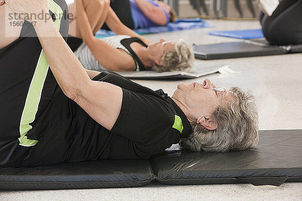 Senioren auf Bodenmatten machen Let-Übungen