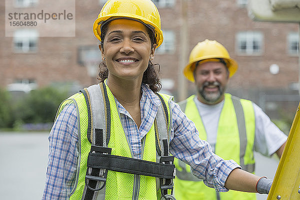 Porträt einer glücklichen Frau und eines glücklichen Mannes  die auf einer Baustelle an einer Stromleitung arbeiten