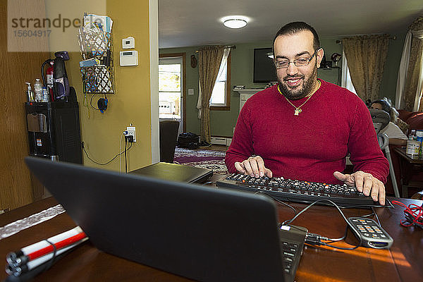 Mann mit Sehbehinderung an seiner Tastatur mit einem Bildschirmlesegerät