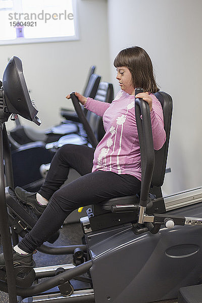 Mädchen mit Down-Syndrom trainiert auf einem Trainingsgerät