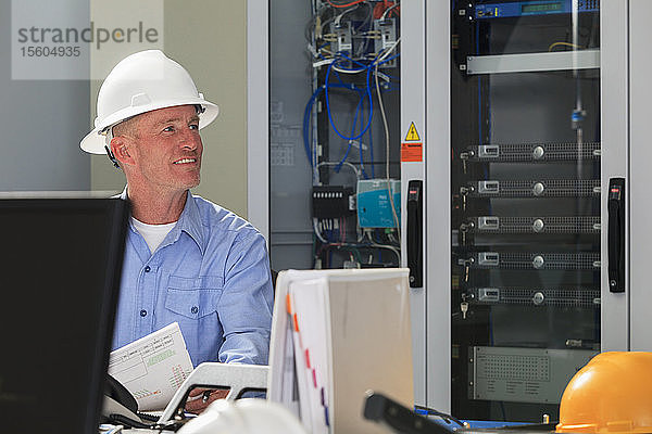 Elektroingenieur  der mit Schaltern und Servern in einem Breitbandkommunikationszentrum arbeitet