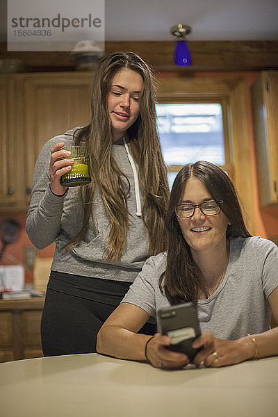 Frau mit Multipler Sklerose spricht mit ihrer Tochter über eine Textnachricht auf dem Telefon