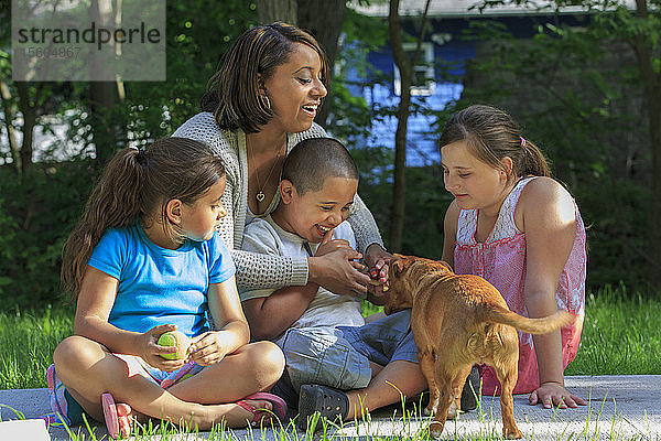 Hispanische Familie mit autistischem Jungen spielt mit einem Hund im Park