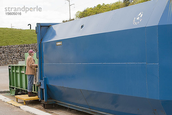 Frau beim Recyceln in der Recyclingpresse von Cardboard Only  die mit einem Container verbunden ist