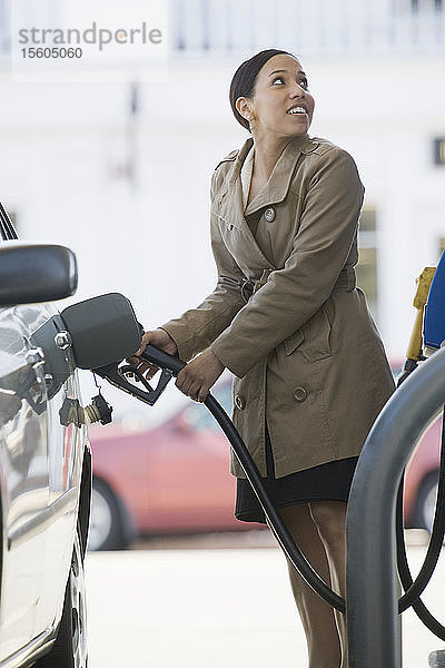 Hispanische Frau beim Betanken eines Autos an einer Tankstelle