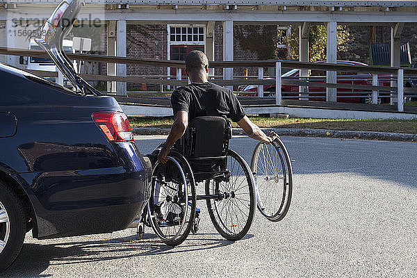 Mann mit Spinaler Meningitis im Rollstuhl beim Einsteigen in sein zugängliches Fahrzeug