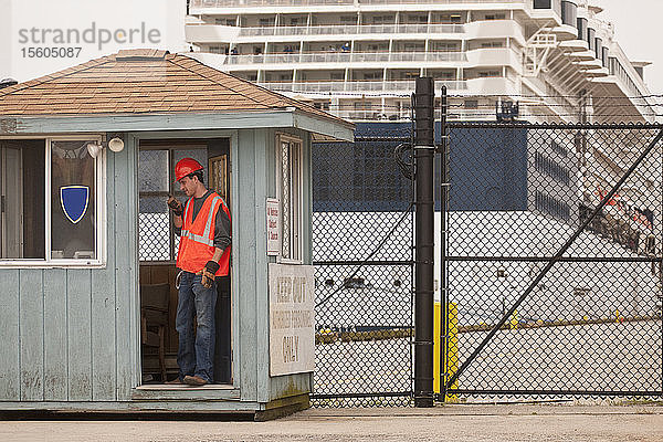 Ingenieur mit Walkie-Talkie an der Sicherheitskontrolle mit einem Passagierschiff im Hintergrund