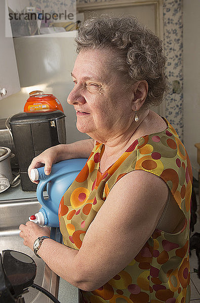 Blinde Seniorin gießt in der Küche Flüssigkeit in ihr Waschbecken